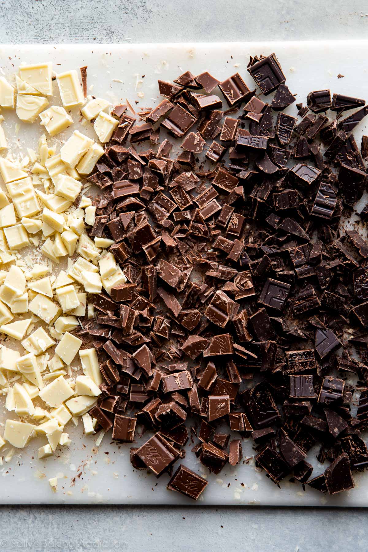 chopped white chocolate, milk chocolate, and dark chocolate on a cutting board