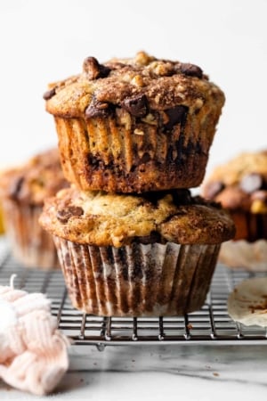 2 banana chocolate chip cinnamon streusel muffins stacked together on wire cooling rack.