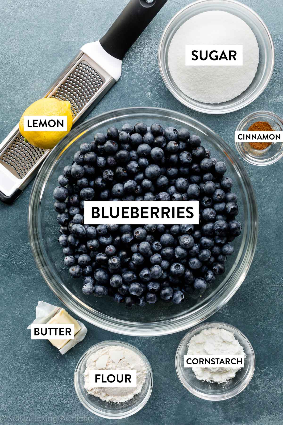 bowls of ingredients including blueberries, sugar, cinnamon, cornstarch, and flour plus butter and 1 lemon.