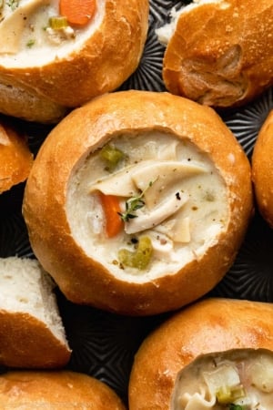 bread bowls on baking sheet filled with chicken noodle soup.