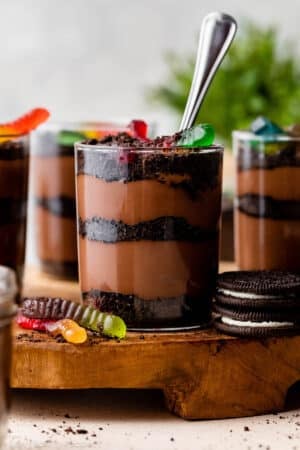 cups of dirt and worms pudding dessert with layers of crushed Oreo cookies, homemade chocolate pudding, and gummy worms on top.