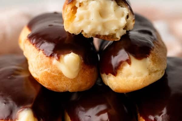 homemade eclairs with pastry cream piled on plate.