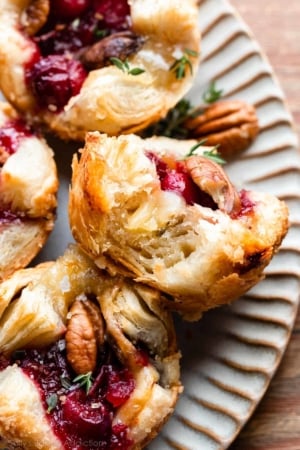 cranberry sauce and brie in a flaky puff pastry tart shown with a bite taken out.