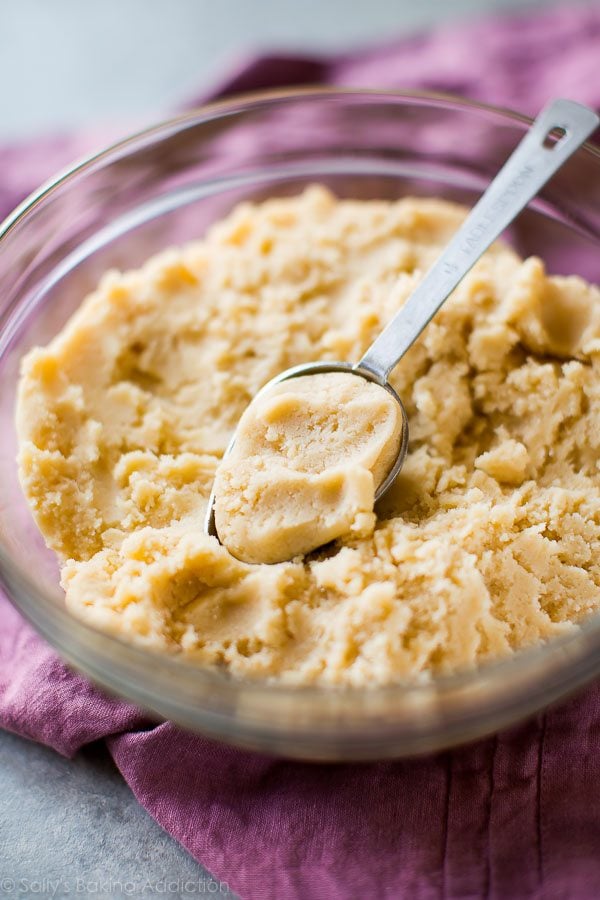 cream cheese sugar cookie dough in a glass bowl with a measuring spoon