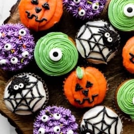 decorated Halloween cupcakes including purple monsters, green monsters, spiders and spider webs, and pumpkin Jack-O-Lanterns.