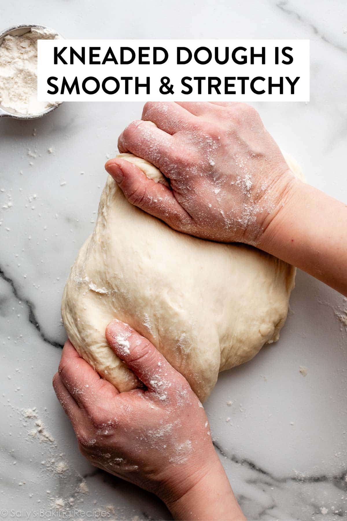 hands stretching and kneading dough on marble counter.