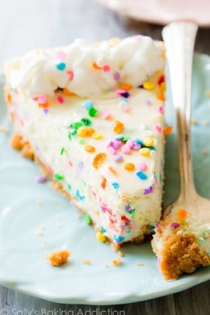 slice of funfetti cheesecake on a blue plate with a fork