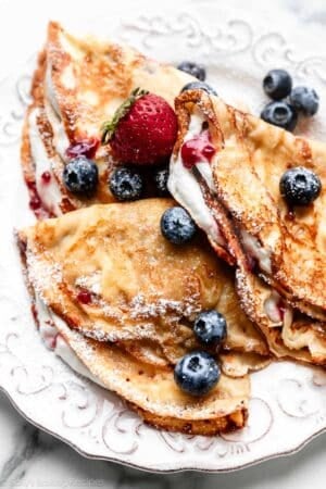 homemade crepes with whipped cream, berries, and raspberry jam.