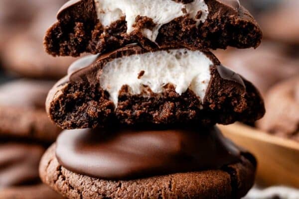 stack of hot cocoa cookies with top two broken open to reveal marshmallow inside.