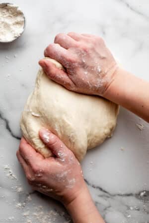 dough in background with text overlay HOW TO KNEAD DOUGH on top.