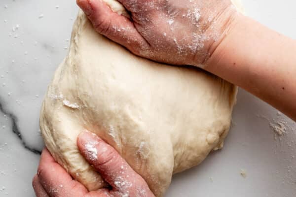 dough in background with text overlay HOW TO KNEAD DOUGH on top.