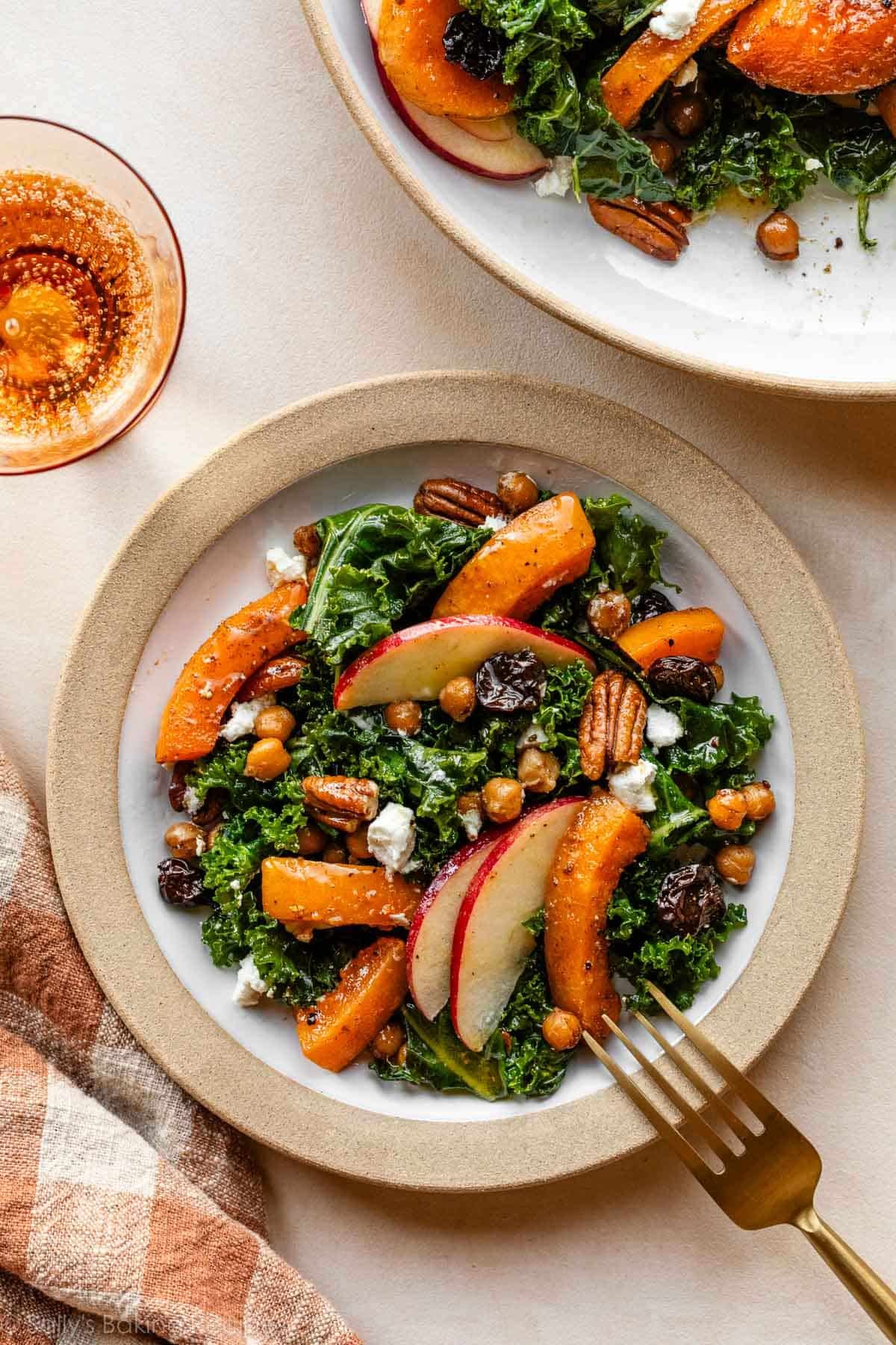 butternut squash and apple fall kale salad on small plate with orange gingham linen next to it.