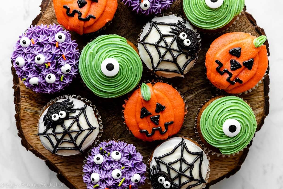 decorated Halloween cupcakes including purple monsters, green monsters, spiders and spider webs, and pumpkin Jack-O-Lanterns.