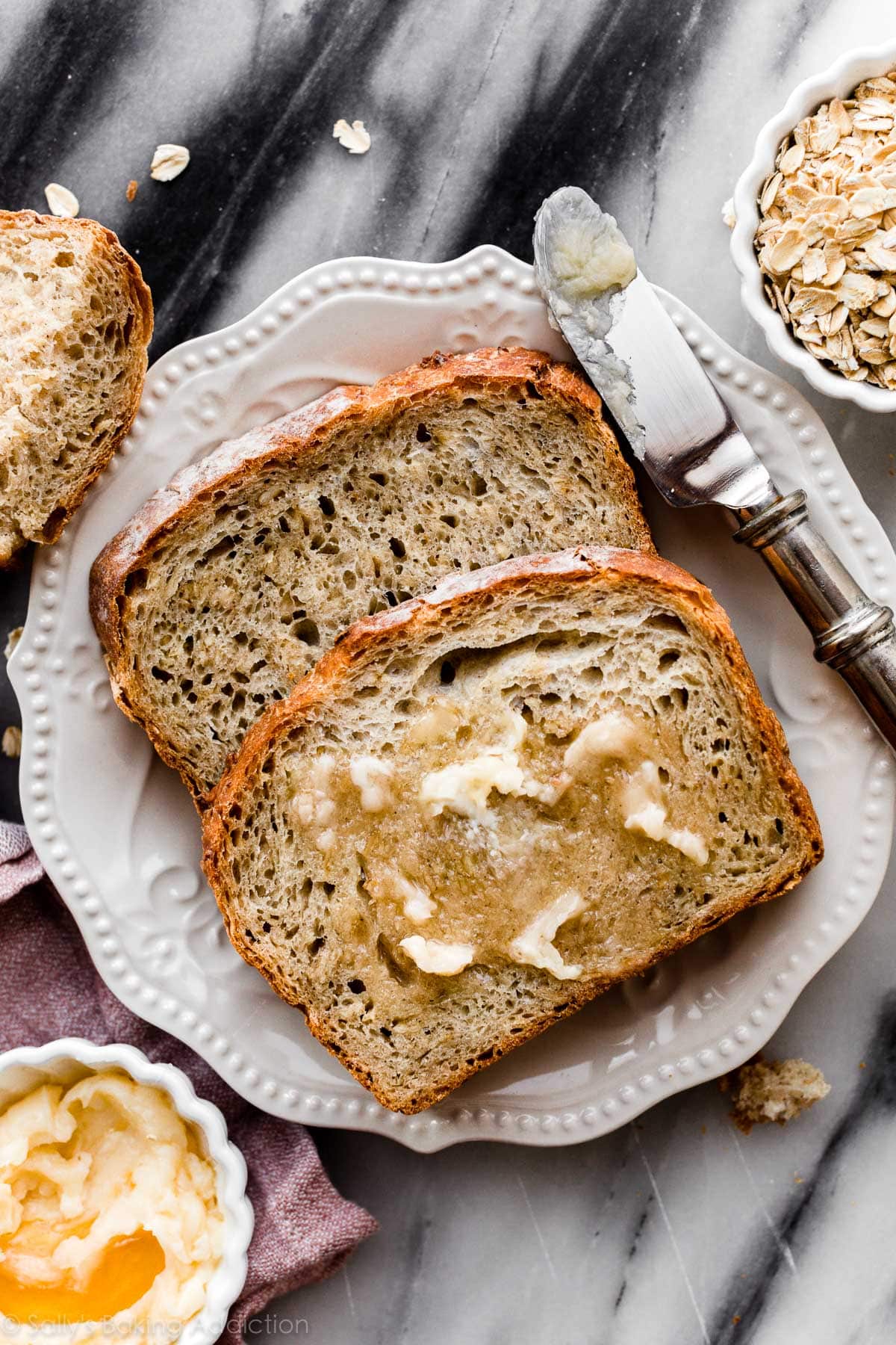 homemade honey oat bread slices with honey butter on white plate