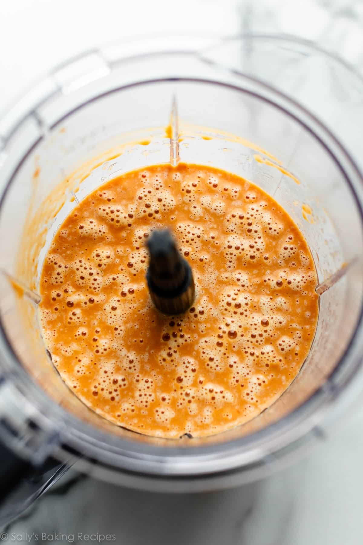 orange batter with bubbles on the surface shown in blender.