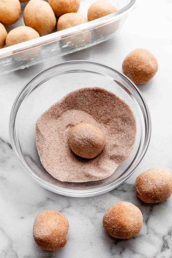 rolling frozen snickerdoodle cookie dough balls in cinnamon sugar.