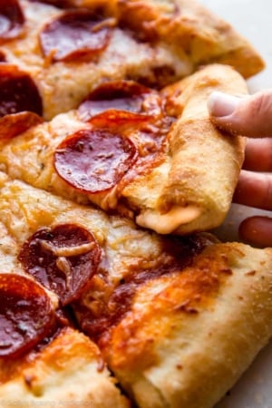 hands pulling out a slice of stuffed crust pizza