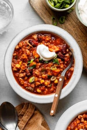 bowl of sweet potato turkey chili with spoon in it and topped with a dollop of sour cream.