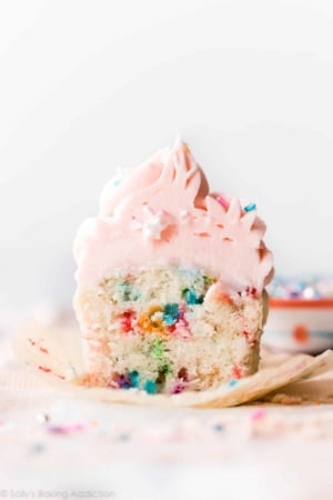 Sprinkle cupcake cut in half showing sprinkles with pink frosting