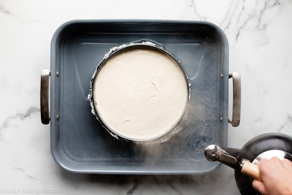 pouring boiling water into roasting pan with cheesecake.